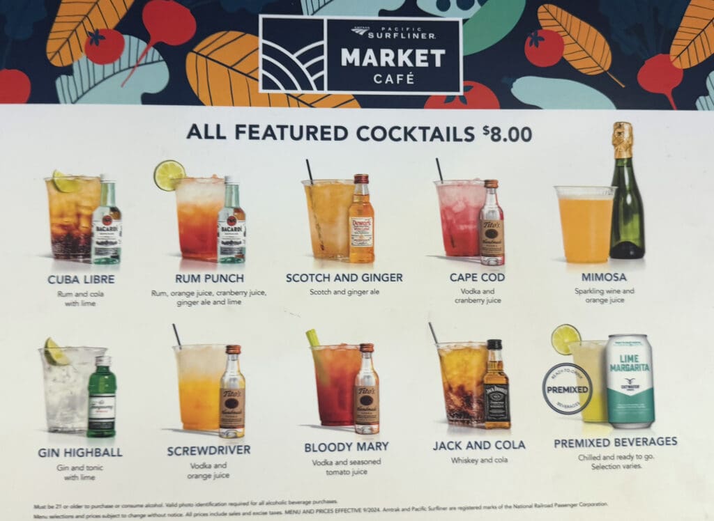 The image is a menu from the Pacific Surfliner Market Café featuring cocktails priced at $8.00. It includes images and descriptions of various drinks:1. **Cuba Libre** - Rum and cola with lime. 2. **Rum Punch** - Rum, orange juice, cranberry juice, ginger ale, and lime. 3. **Scotch and Ginger** - Scotch and ginger ale. 4. **Cape Cod** - Vodka and cranberry juice. 5. **Mimosa** - Sparkling wine and orange juice. 6. **Gin Highball** - Gin and tonic with lime. 7. **Screwdriver** - Vodka and orange juice. 8. **Bloody Mary** - Vodka and seasoned tomato juice. 9. **Jack and Cola** - Whiskey and cola. 10. **Premixed Beverages** - Chilled and ready to go, selection varies. The background has a colorful design with leaves and circles.