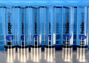 The image shows a row of transparent, cylindrical awards with blue accents. The awards are labeled "freddie awards" and have the year "2025" on them. They are standing upright on a reflective surface, and the name "Wells Fargo" is visible on some of the awards.