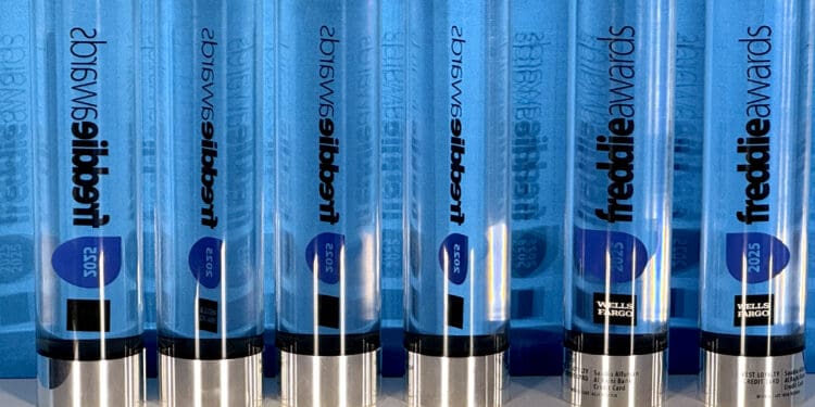 The image shows a row of transparent, cylindrical awards with blue accents. The awards are labeled "freddie awards" and have the year "2025" on them. They are standing upright on a reflective surface, and the name "Wells Fargo" is visible on some of the awards.