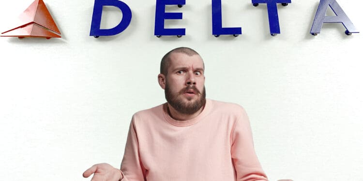 A person with a beard and a puzzled expression is shrugging their shoulders, wearing a pink sweater. They are standing in front of a wall with the word "DELTA" and a red triangular logo.