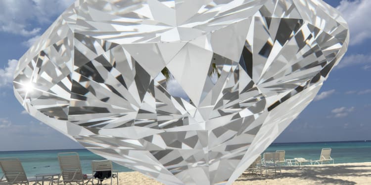 A large, transparent diamond is digitally superimposed over a beach scene. The beach has white sand, several lounge chairs, and a small table. The ocean is visible in the background under a partly cloudy sky.