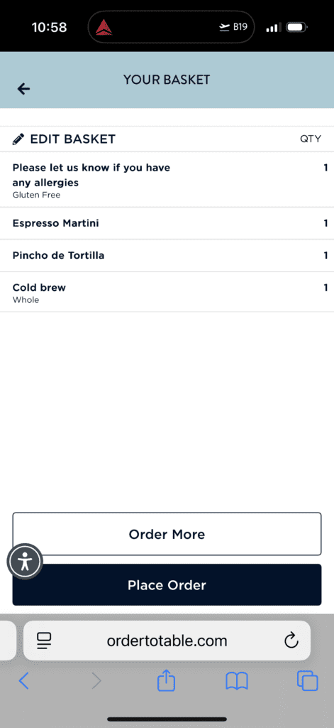 The image shows a mobile screen displaying a basket summary from an online ordering platform. The header reads "YOUR BASKET" with an option to edit the basket. The items listed are: 1. A note asking to inform about any allergies, marked as "Gluten Free." 2. Espresso Martini, quantity 1. 3. Pincho de Tortilla, quantity 1. 4. Cold brew, marked as "Whole," quantity 1. At the bottom, there are buttons labeled "Order More" and "Place Order." The website URL "ordertotable.com" is visible at the bottom of the screen.