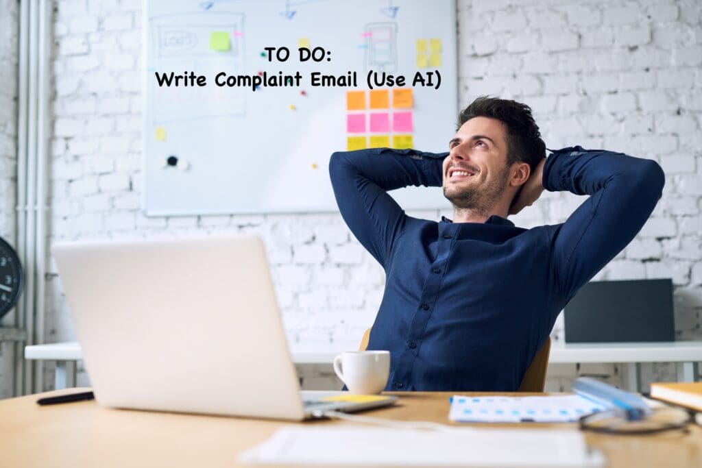 A man is sitting at a desk with a laptop and a cup of coffee, leaning back in his chair with his hands behind his head, smiling. Behind him is a whiteboard with sticky notes and the text "TO DO: Write Complaint Email (Use AI)" written on it. The setting appears to be a modern office with a brick wall.