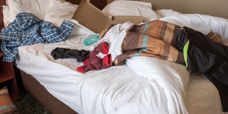 messy hotel room bed after a night of partying