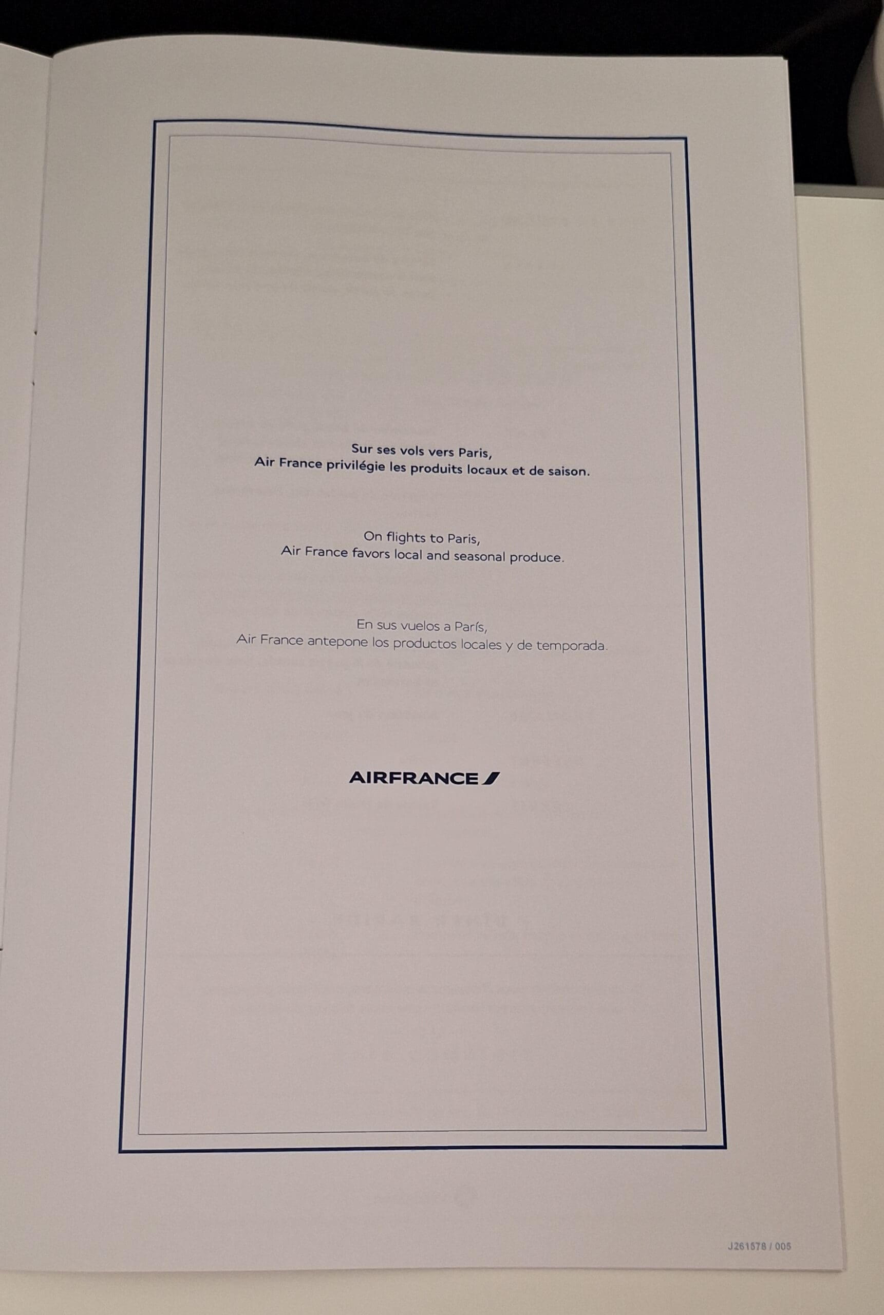 The image shows a page from an Air France document. It contains text in three languages: French, English, and Spanish. The text states that on flights to Paris, Air France favors local and seasonal produce. The Air France logo is at the bottom of the page. The page is bordered with a thin blue line.