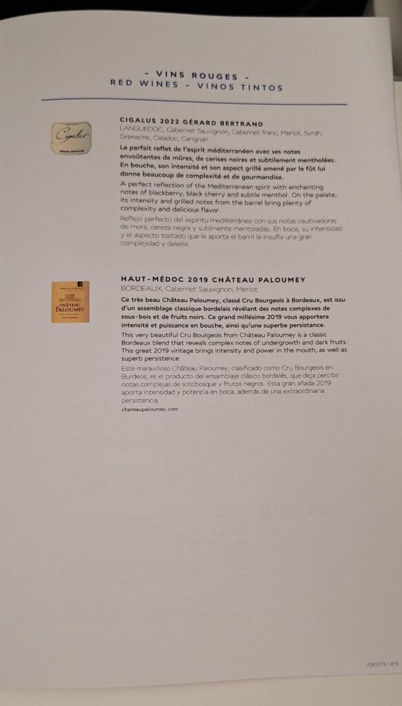 The image shows a page from a wine menu or catalog featuring two red wines. The top section describes "Cigalus 2022 Gérard Bertrand" from Languedoc, listing grape varieties and providing tasting notes in French, English, and Spanish. The bottom section describes "Haut-Médoc 2019 Château Paloumey" from Bordeaux, also with grape varieties and tasting notes in the same three languages. Each wine description includes a small image of the wine label. The page is titled "Vins Rouges - Red Wines - Vinos Tintos."