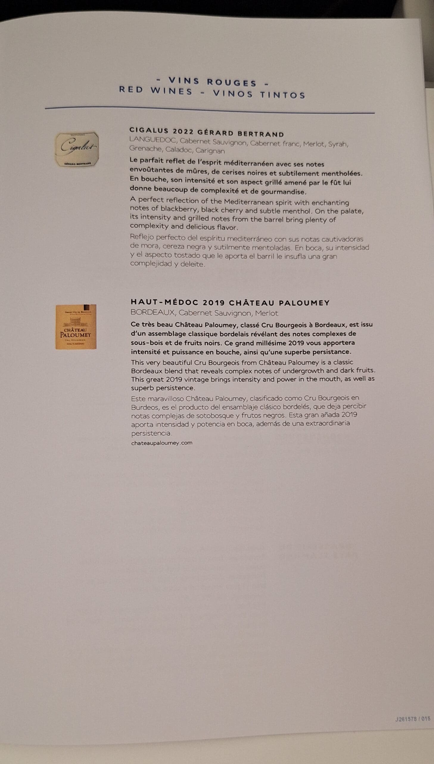 The image shows a page from a wine menu or catalog featuring two red wines. The top section describes "Cigalus 2022 Gérard Bertrand" from Languedoc, listing grape varieties and providing tasting notes in French, English, and Spanish. The bottom section describes "Haut-Médoc 2019 Château Paloumey" from Bordeaux, also with grape varieties and tasting notes in the same three languages. Each wine description includes a small image of the wine label. The page is titled "Vins Rouges - Red Wines - Vinos Tintos."