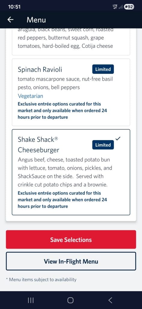 The image shows a section of an in-flight menu on a mobile device screen. It includes two meal options: "Spinach Ravioli" and "Shake Shack Cheeseburger." The Spinach Ravioli is described as having tomato mascarpone sauce, nut-free basil pesto, onions, and bell peppers, and is marked as vegetarian. The Shake Shack Cheeseburger includes Angus beef, cheese, a toasted potato bun, lettuce, tomato, onions, pickles, and ShackSauce, served with crinkle-cut potato chips and a brownie. Both options are labeled as "Limited" and require ordering 24 hours prior to departure. There are buttons for "Save Selections" and "View In-Flight Menu" at the bottom.