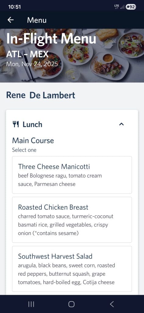 The image shows an in-flight menu for a flight from ATL to MEX on November 24, 2025. The menu is for lunch and offers three main course options: 1. Three Cheese Manicotti with beef Bolognese ragu, tomato cream sauce, and Parmesan cheese. 2. Roasted Chicken Breast with charred tomato sauce, turmeric-coconut basmati rice, grilled vegetables, and crispy onion (contains sesame). 3. Southwest Harvest Salad with arugula, black beans, sweet corn, roasted red peppers, butternut squash, grape tomatoes, hard-boiled egg, and Cotija cheese. The top of the image shows a background with various plated dishes.