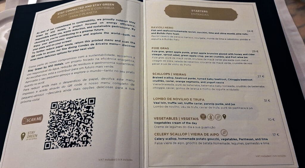This image shows a restaurant menu. The left page discusses the "Stay Green" initiative by H10 Hotels, promoting sustainability and offering a QR code for accessing the menu online. The right page lists starters with descriptions and prices, including dishes like Ravioli Nero, Foie Gras, Scallops, Lombo de Novilho e Trufa, Vegetables, and Celery Scallop. The text is in both English and Portuguese.