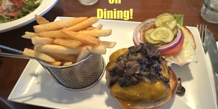 A plate of food featuring a cheeseburger topped with mushrooms, lettuce, tomato, pickles, and red onion, served with a side of French fries in a metal basket. The text "5X Points on Dining!" is displayed above the food. A salad is partially visible in the background.