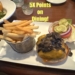 A plate of food featuring a cheeseburger topped with mushrooms, lettuce, tomato, pickles, and red onion, served with a side of French fries in a metal basket. The text "5X Points on Dining!" is displayed above the food. A salad is partially visible in the background.