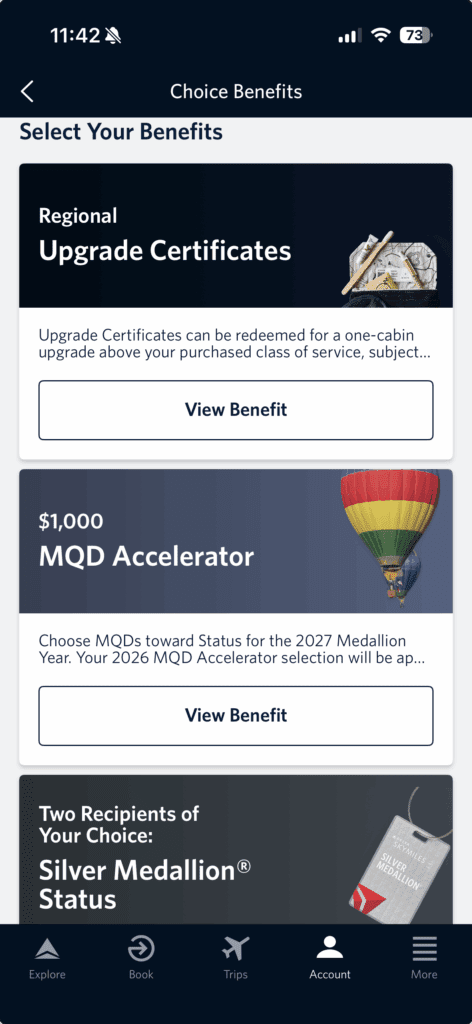The image is a screenshot of a mobile app interface displaying "Choice Benefits" options. It includes three benefit options:

1. "Regional Upgrade Certificates" with a description about redeeming for a one-cabin upgrade. There is a "View Benefit" button.
2. "$1,000 MQD Accelerator" with a description about choosing MQDs toward status for the 2027 Medallion® Year. There is a "View Benefit" button.
3. "Two Recipients of Your Choice: Silver Medallion® Status" with an image of a Silver Medallion® tag.

The top of the screen shows the time and battery status, and the bottom has navigation icons for Explore, Book, Trips, Account, and More.