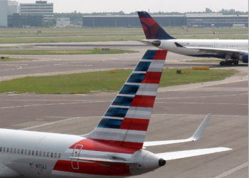 View Of American Airlines,Delta Air Lines Passenger Airplane Taxiing To Take Off From Amsterdam Schiphol International Airport In The Netherlands Europe.Including KLM Office Building Exterior