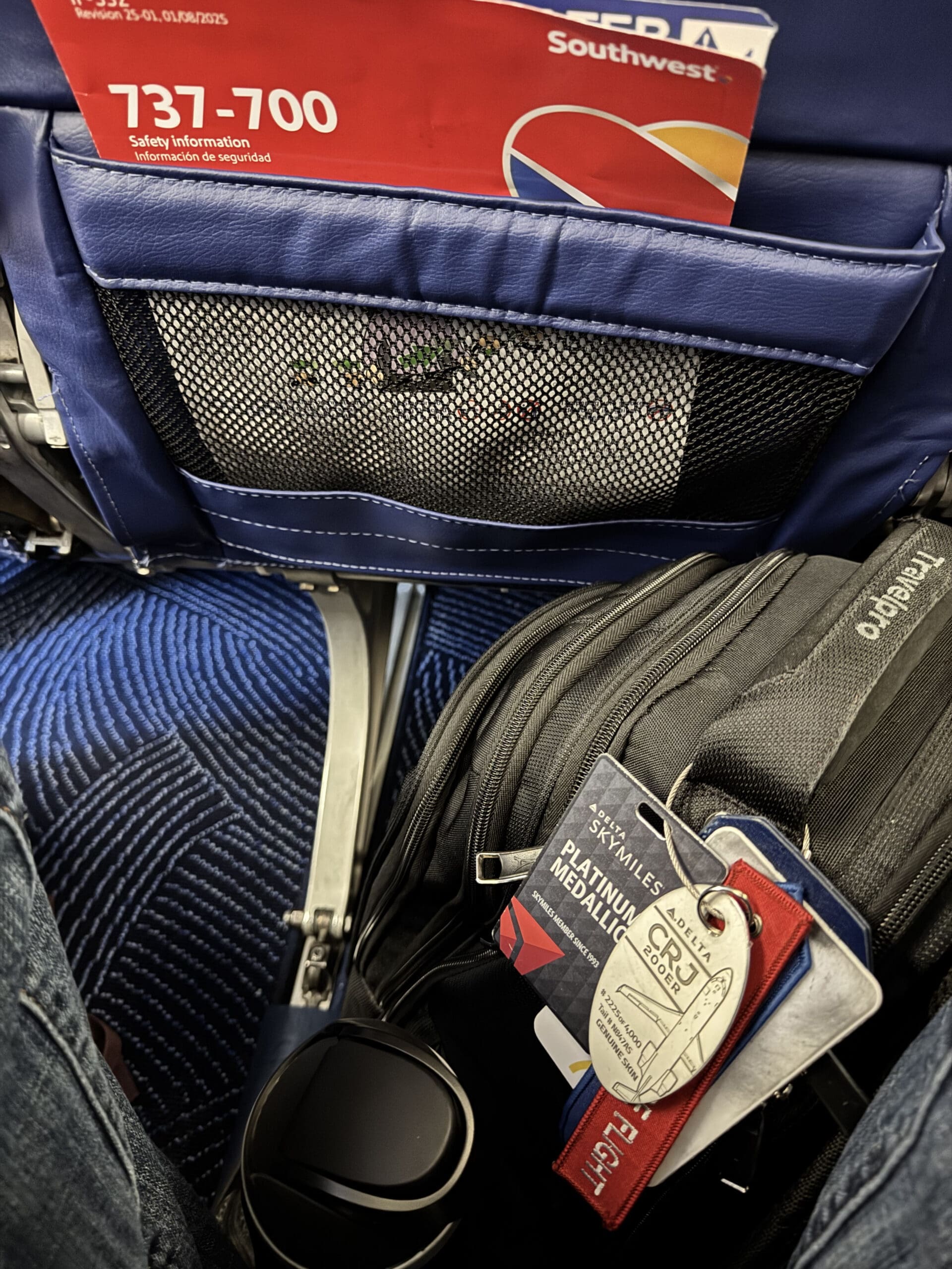 Carry-on bag under a Southwest 737-700 seat with a Delta SkyMiles Platinum Medallion luggage tag attached.