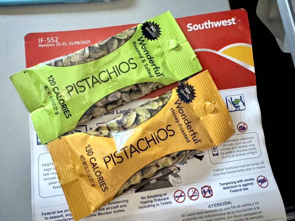 Two Wonderful Pistachios snack packs — Roasted & Salted and Honey Roasted — resting on a Southwest safety card