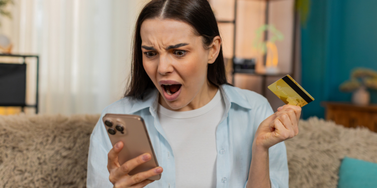 Woman worried while checking her credit card balance on her phone
