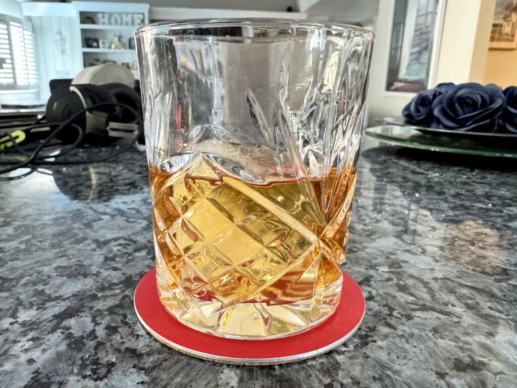 A whiskey glass atop a coaster made from a Qantas 747 aircraft skin from Planetags