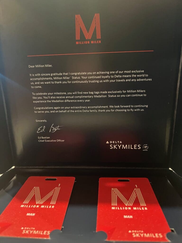 The image shows a congratulatory letter and two red bag tags from Delta Air Lines for achieving "Million Miler" status. The letter, signed by Ed Bastian, CEO of Delta, expresses gratitude for the recipient's loyalty and outlines the benefits of the status, including complimentary Medallion® Status. The bag tags are branded with "Million Miler" and "Delta SkyMiles."